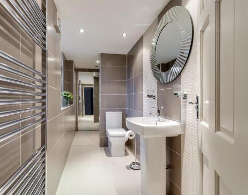 a bathroom with a toilet and a sink and a mirror at East Row Lodge in Whitby