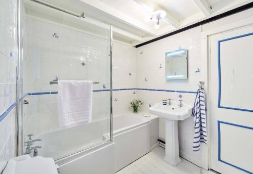 a white bathroom with a shower and a sink at Rigg Cottage in Whitby