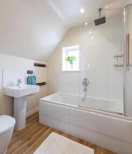 a white bathroom with a tub and a sink at Sunny Corner Cottage in Filey