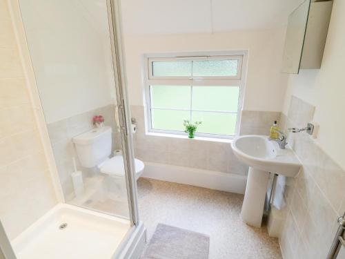 ein Badezimmer mit Toilette und Waschbecken und einem Fenster in der Unterkunft 4 Rose Cottages in Looe