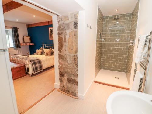 ein Bad mit einer Dusche und ein Schlafzimmer mit einem Bett in der Unterkunft The Old Workshop in Belford