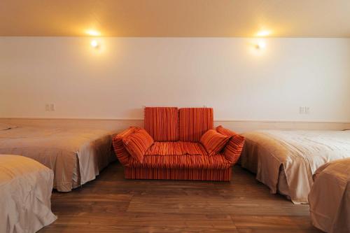 an orange chair in a room with two beds at SILVER SPRAY MtFuji view Yamanakako in Yamanakako