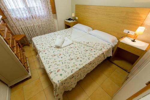 a small bedroom with a bed with a floral blanket at Villa Turística de Cazorla in Cazorla