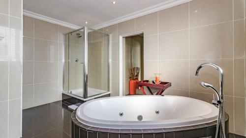 a bath tub in a bathroom with a shower at Silver Oaks Boutique Hotel in Durban
