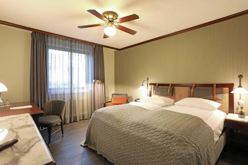 a hotel room with a bed and a ceiling fan at Mercure Hotel Frankfurt Airport Langen in Langen