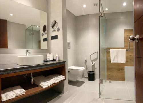 ein Bad mit einem Waschbecken, einem WC und einer Dusche in der Unterkunft The Rosefinch Sarovar Portico in Bhīm Tāl