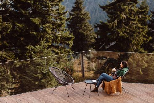 a woman sitting in a chair on a deck with a baby at Ski&Sun Apartamenty in Świeradów-Zdrój