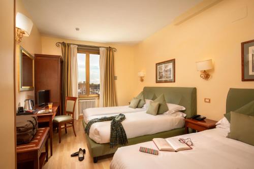 um quarto de hotel com duas camas e uma secretária em Hotel Colosseum em Roma