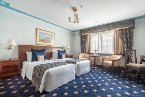 a hotel room with two beds and a desk at Sarova Stanley in Nairobi