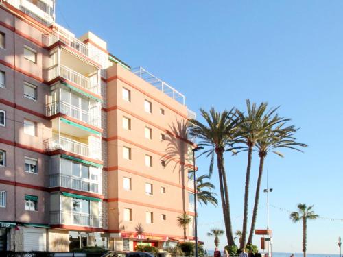 a tall pink building with palm trees in front of it at Apartment La Goleta by Interhome in Benidorm