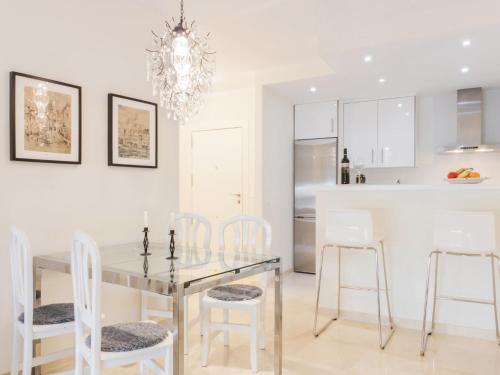 cocina y comedor con mesa de cristal y sillas blancas en Apartment Puerto Paraiso-1 by Interhome, en Estepona