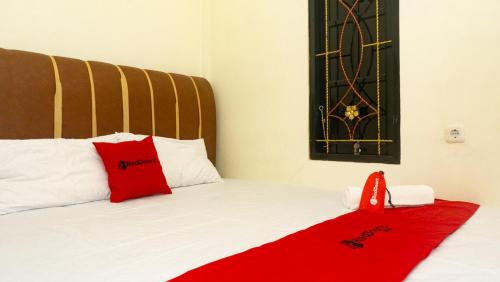 a bedroom with a bed with a red blanket on it at RedDoorz near Sentani Airport Jayapura in Jayapura