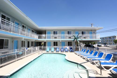 a swimming pool with chairs and a building at Stardust Motel in Wildwood