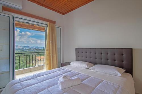 een slaapkamer met een groot bed en een groot raam bij Family Private Homes & Sea View in Lithakia