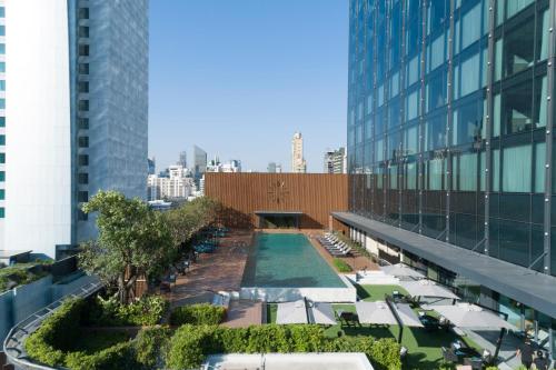 曼谷的住宿－Carlton Hotel Bangkok Sukhumvit，享有带游泳池和椅子的大楼的顶部景致