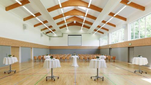 a banquet hall with tables and chairs and a screen at Dorint Parkhotel Siegen in Siegen