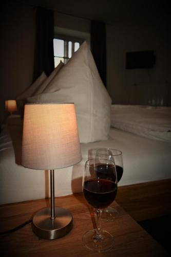 a lamp and a glass of wine next to a bed at Landgut Stetter in Schöllnach