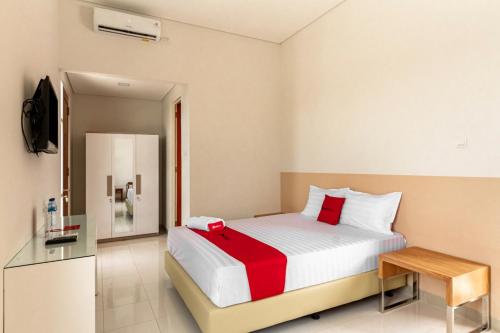 a bedroom with a large bed with a red blanket at RedDoorz Syariah @ Kebraon in Kebraon