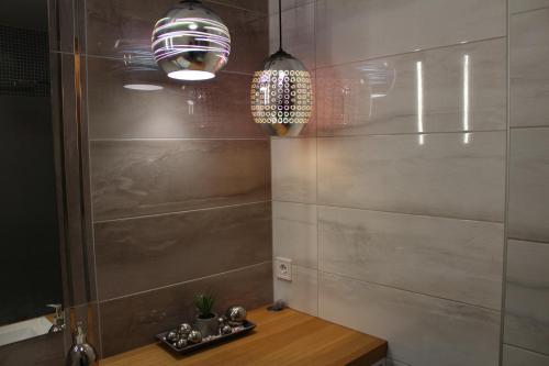 een badkamer met 2 hanglampen en een houten tafel bij Quelle-Apartman in Győr