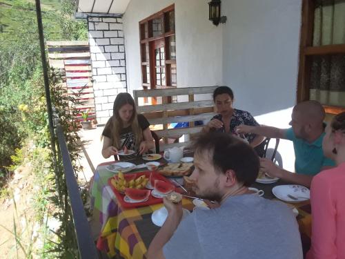 Eine Gruppe von Menschen, die an einem Tisch sitzen und Essen essen. in der Unterkunft Lily adam's peak in Nallathanniya