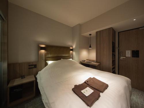 a hotel room with a bed with a brown bag on it at hotel H2 TRIP&BUSINESS NAGASAKI in Nagasaki