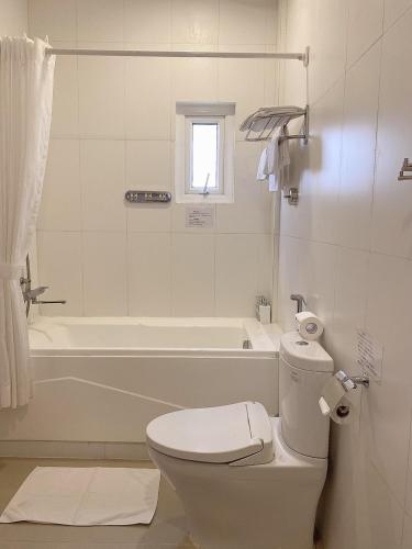 a white bathroom with a toilet and a bath tub at Phạm Vân Sakura Hotel in Thuan An