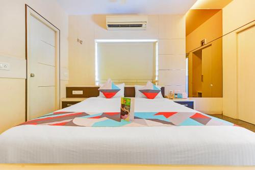 a bedroom with a large white bed with colorful pillows at FabExpress B Zone - Nr US Consulate in Chennai