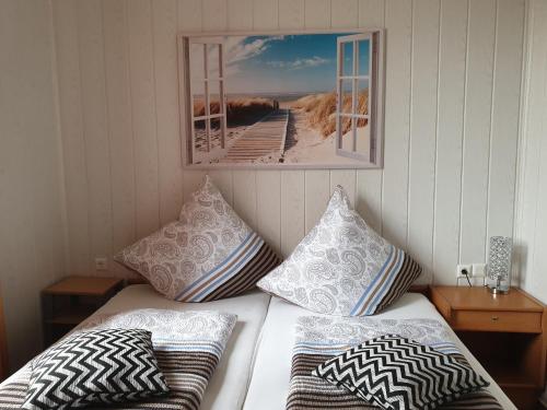 a bed with pillows and a picture on the wall at Pension Am Mellensee in Saalow