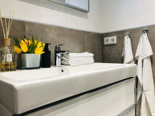 a white sink in a bathroom with flowers and towels at Blue City Apartments in Lübeck