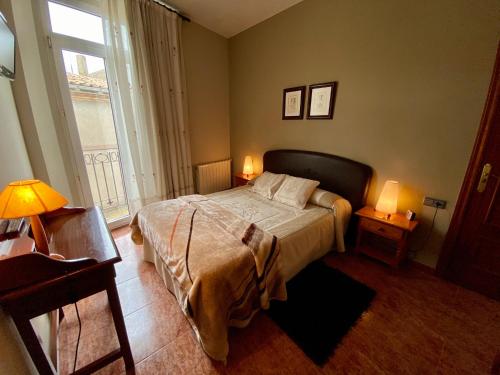 a bedroom with a bed with two lamps and a window at Hostal Bonavista in Cervera