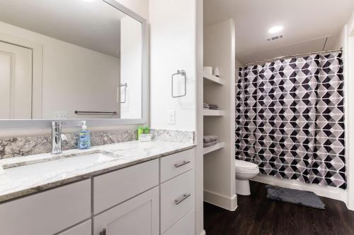 a white bathroom with a sink and a toilet at StayOvr at LegacyWest in Plano