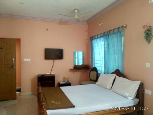 a bedroom with a bed and a tv and a window at Aruvi Hotel in Yelagiri