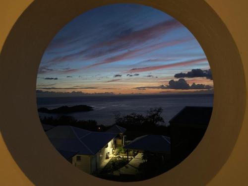 a view of a sunset through a round window at Nono in Bouillante