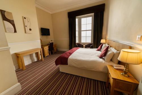 a hotel room with a bed and a window at Hotel Prince Regent in Weymouth