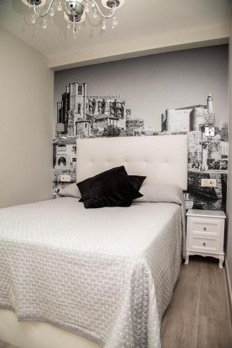 a bedroom with a white bed with a black pillow at Alojamientos Rooms Catamarán in Castro-Urdiales