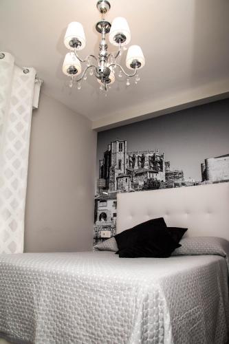 a bedroom with a bed with a chandelier at Alojamientos Rooms Catamarán in Castro-Urdiales