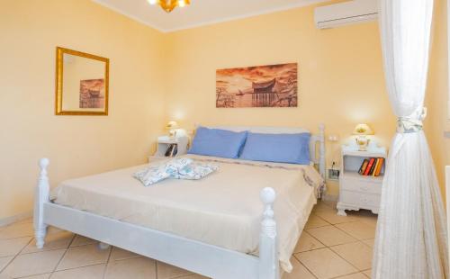 a bedroom with a white bed with blue pillows at Villa Christelle Luxury Pescoluse by HDSalento in Marina di Pescoluse
