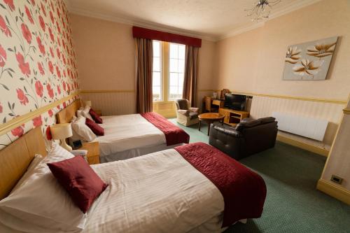 a hotel room with two beds and a living room at Hotel Prince Regent in Weymouth