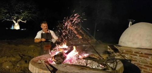a man is standing in front of a fire at La Ceiba in San Fernando del Valle de Catamarca