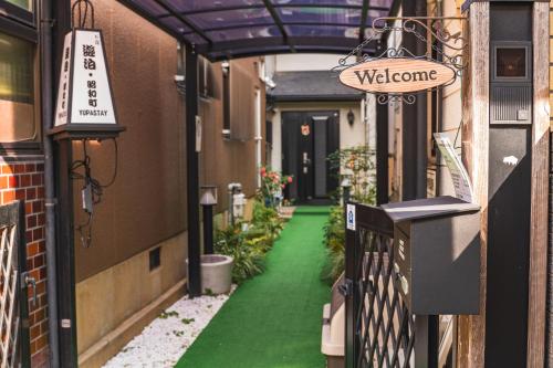 a walkway with green flooring and a sign that reads welcome at 遊泊昭和町YupaStay in Osaka