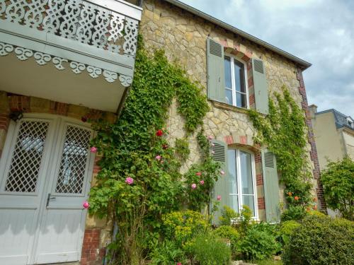 una casa de piedra con flores a un lado. en La Paresse en Ville, en Bayeux