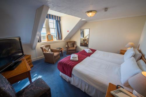 a hotel room with a bed and a flat screen tv at Hotel Prince Regent in Weymouth