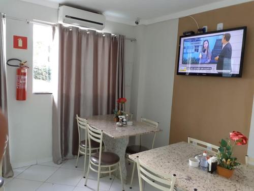 sala de estar con mesa y TV en la pared en Pousada Santa Maria en Euclides da Cunha