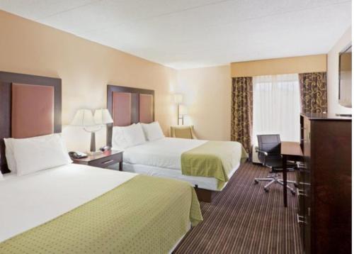 チャールストンにあるHoliday Inn Express Hotel & Suites Charleston-Southridge, an IHG Hotelのベッド2台とデスクが備わるホテルルームです。
