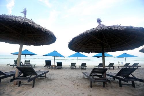 a group of chairs and umbrellas on a beach at Tan Doan An Bang center beach villas in An Bang