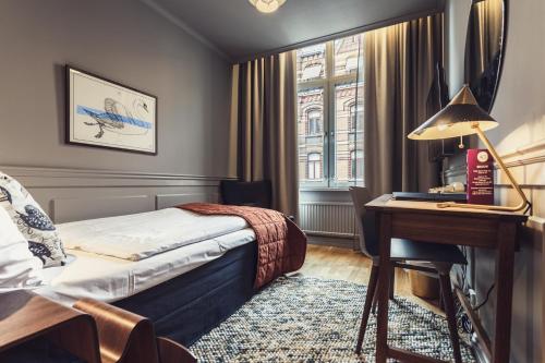 a bedroom with a bed and a desk and a window at Hotel Poseidon in Gothenburg