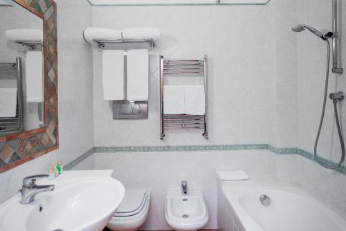 a white bathroom with a sink and a toilet at Hotel Montana in Massa Lubrense