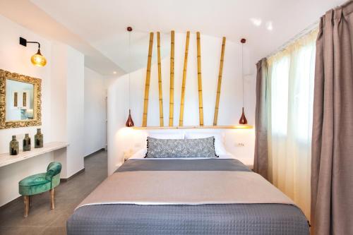 a bedroom with a large bed and a green chair at Abasa Suites in Fira