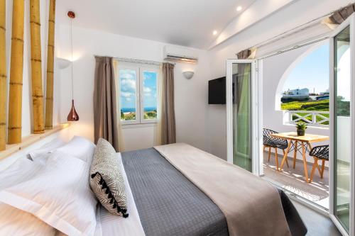 a bedroom with a large bed and a balcony at Abasa Suites in Fira
