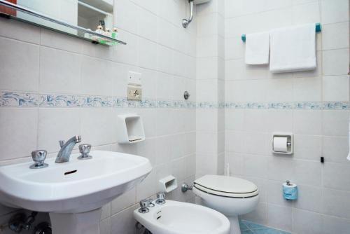 a white bathroom with a sink and a toilet at Hotel Montana in Massa Lubrense